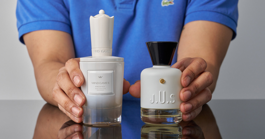 A man in blue shirt holding a bottle of MAISON J.U.S. SUPERFUSION Eau De Parfum and MIND GAMES Prodigy Extrait de Parfum.
