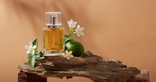 A chypre perfume sitting on a rock next to a lime and flowers.