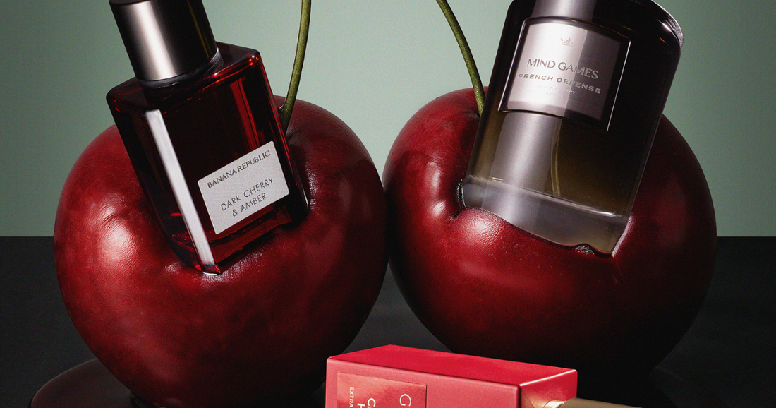 Two perfume bottles embedded in two large cherries with a bottle laying on it's side on the ground.
