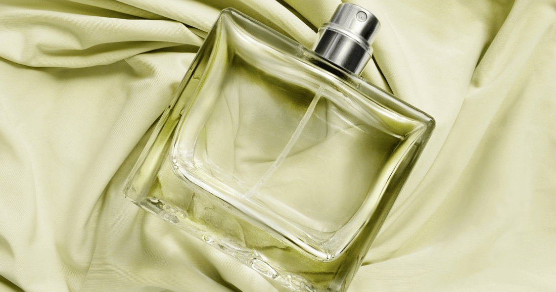 A bottle of clear perfume laying on a green colored cloth.