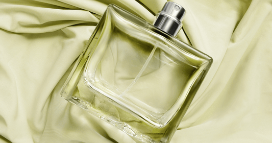 A bottle of clear perfume laying on a green colored cloth.