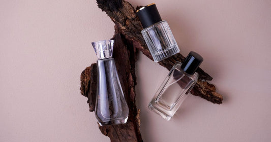 Oud fragrances on a piece of wood against a light pink background.