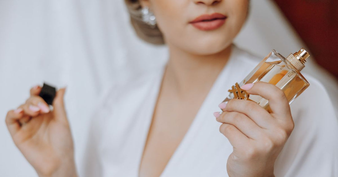 A fancy, elegant woman looks at a bottle of perfume.