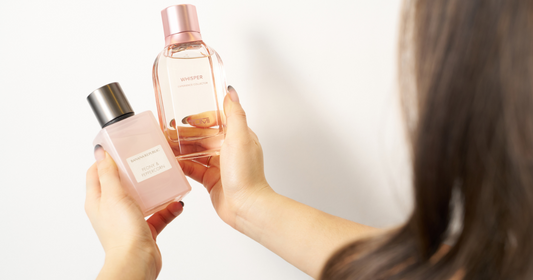 A woman looking at two perfumes to use for layering.